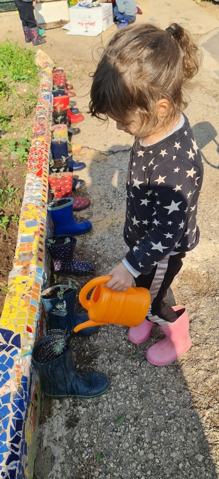 ילדה משקה עציצים בגן ירוק