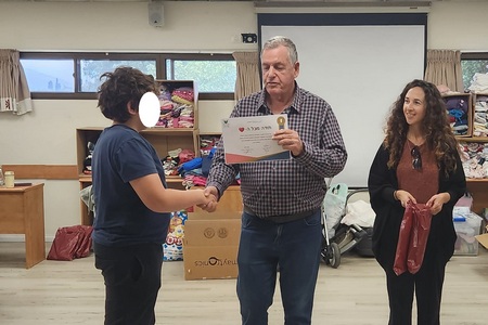 ראש המועצה, אייל בצר, מעניק תעודת הוקרה לאחד התלמידים