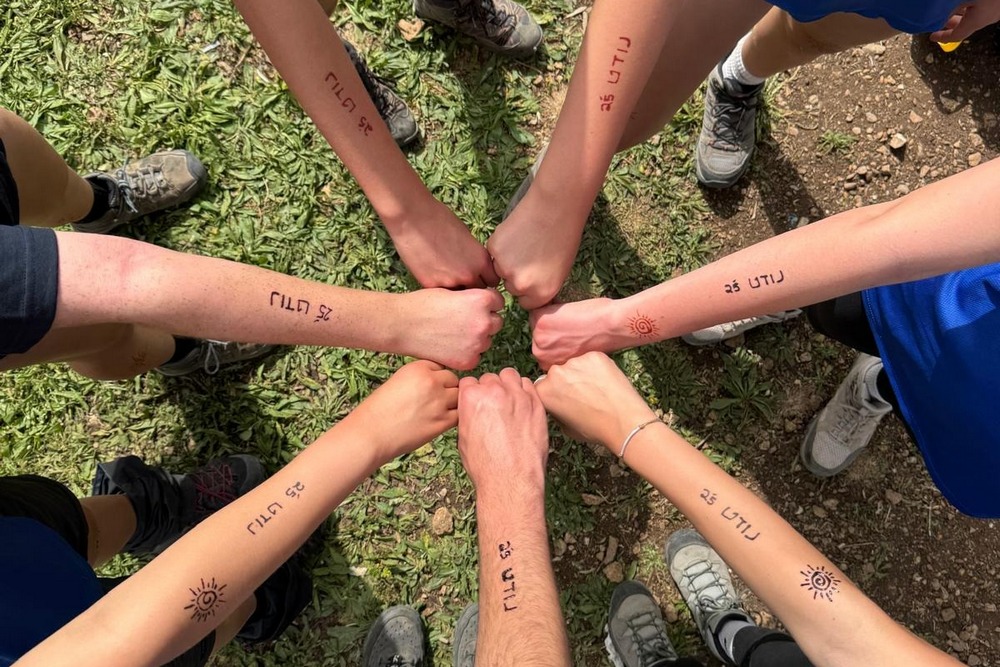 קבוצת בני ובנות נוער במעגל עם האגרופים במרכז המעגל